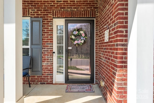 view of exterior entry featuring brick siding
