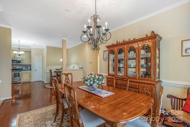 dining room with dark wood finished floors, ornamental molding, and an inviting chandelier