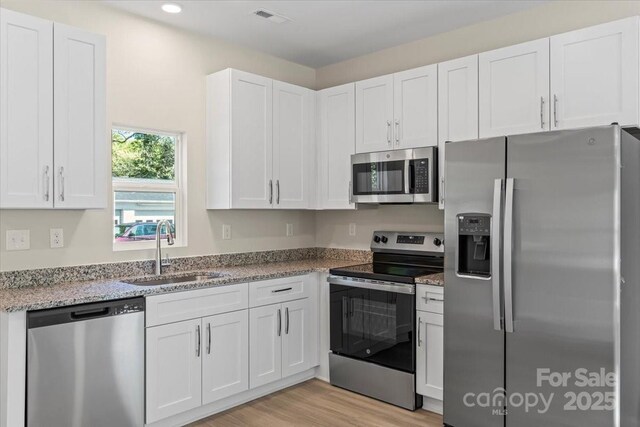 808 Carolyn Ave, Kannapolis, NC 28083 - kitchen with white cabinets, visible vents, a sink, light wood-type flooring, and appliances with stainless steel finishes