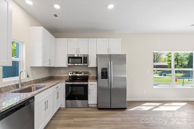 808 Carolyn Ave, Kannapolis, NC 28083 - kitchen with a sink, light wood-style floors, white cabinetry, appliances with stainless steel finishes, and light stone countertops
