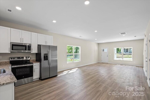 808 Carolyn Ave, Kannapolis, NC 28083 - kitchen with white cabinets, light stone counters, visible vents, light wood-type flooring, and appliances with stainless steel finishes