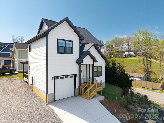view of front of home featuring a garage, driveway, fence, and roof with shingles