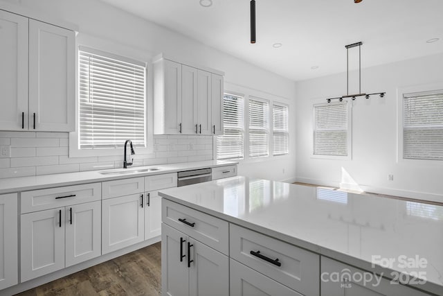 kitchen featuring white cabinets, a sink, tasteful backsplash, dark wood finished floors, and dishwasher