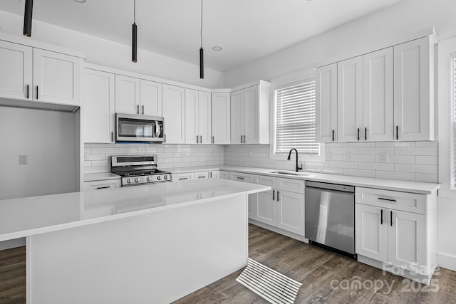 kitchen featuring dark wood-style floors, a sink, light countertops, a kitchen island, and appliances with stainless steel finishes