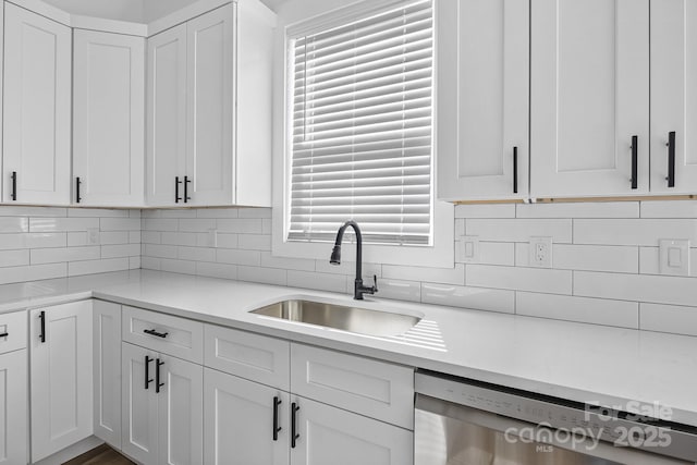 kitchen featuring dishwasher, light countertops, a sink, and white cabinetry