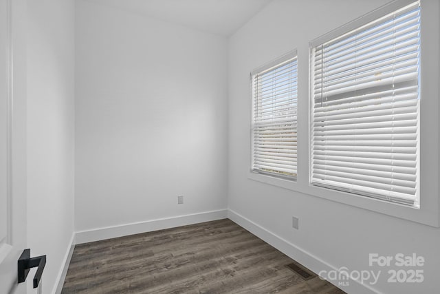 unfurnished room featuring baseboards, visible vents, and dark wood-style floors