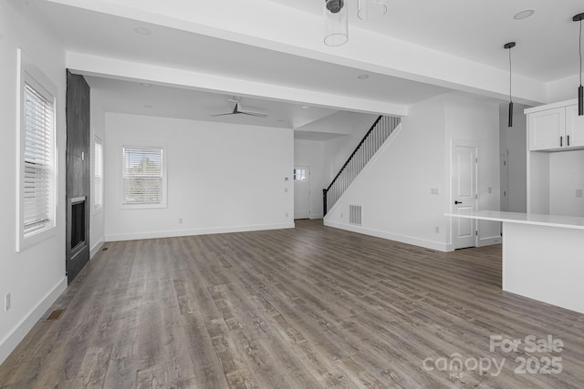unfurnished living room featuring visible vents, a ceiling fan, wood finished floors, stairs, and a fireplace