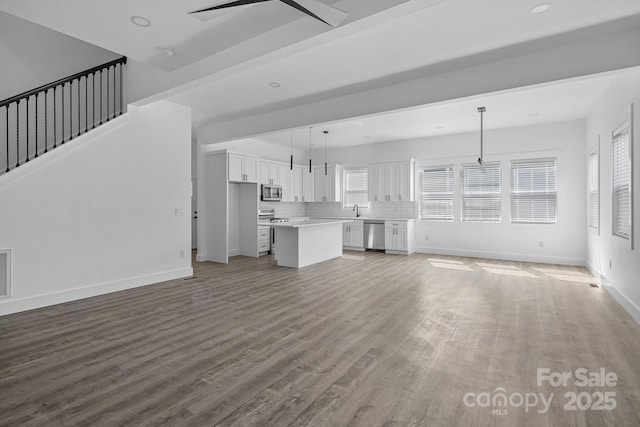 unfurnished living room with ceiling fan, baseboards, a healthy amount of sunlight, and wood finished floors