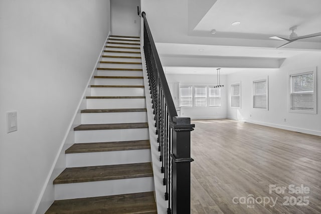 staircase featuring wood finished floors, a ceiling fan, baseboards, and recessed lighting