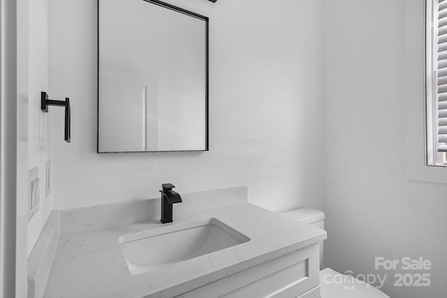 half bath featuring vanity and toilet