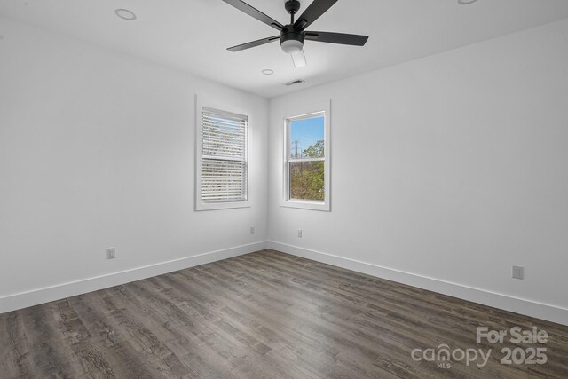 spare room with baseboards, visible vents, dark wood-style floors, and ceiling fan