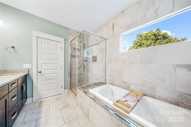 full bathroom with a stall shower, a bath, vanity, and baseboards