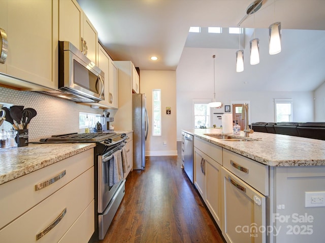 kitchen with stainless steel appliances, a sink, dark wood-type flooring, decorative backsplash, and baseboards