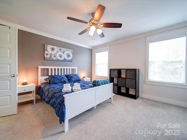 carpeted bedroom with crown molding, baseboards, and a ceiling fan