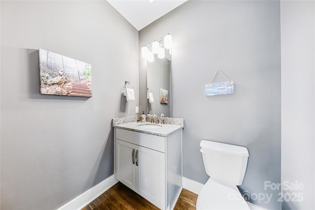 bathroom with wood finished floors, toilet, baseboards, and vanity