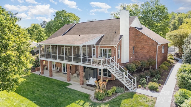 back of property featuring a sunroom, a patio, brick siding, and a chimney