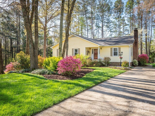 single story home featuring a chimney and a front lawn