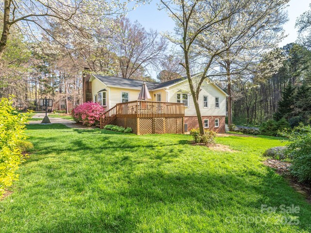 rear view of house with a lawn, a chimney, and a deck