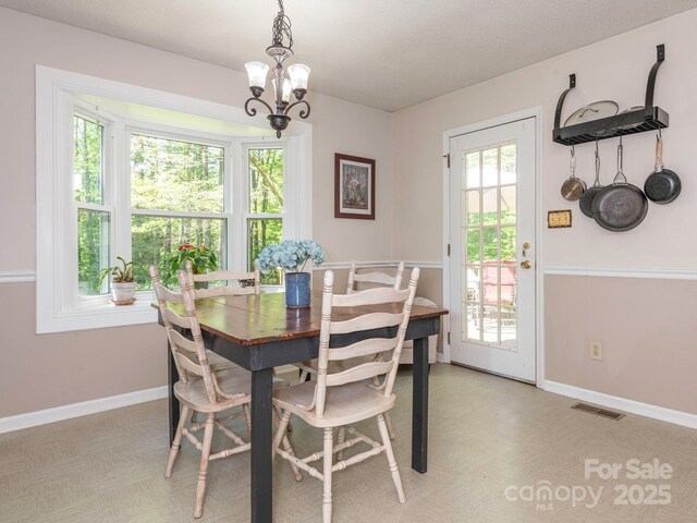 dining area with an inviting chandelier, visible vents, and baseboards