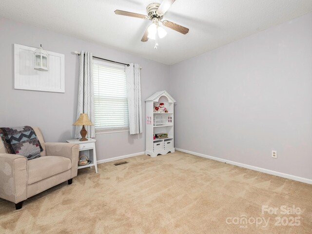 sitting room with ceiling fan, light carpet, visible vents, and baseboards
