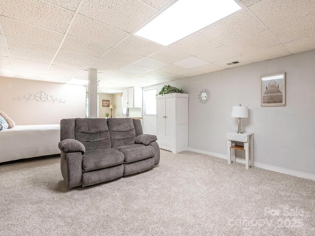 living room featuring carpet floors, visible vents, baseboards, and a paneled ceiling