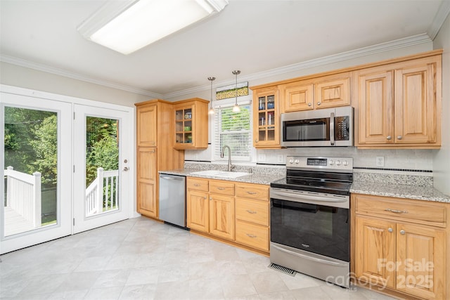 kitchen with light stone countertops, ornamental molding, a sink, and appliances with stainless steel finishes