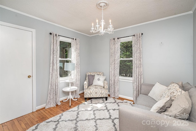 sitting room with wood finished floors, crown molding, baseboards, a chandelier, and a textured ceiling