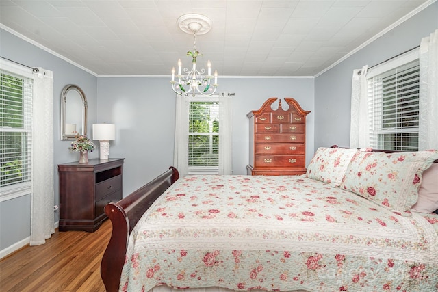 bedroom with wood finished floors, ornamental molding, baseboards, and a notable chandelier