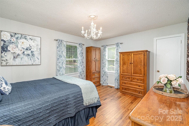 bedroom featuring light wood-type flooring, a textured ceiling, and a notable chandelier