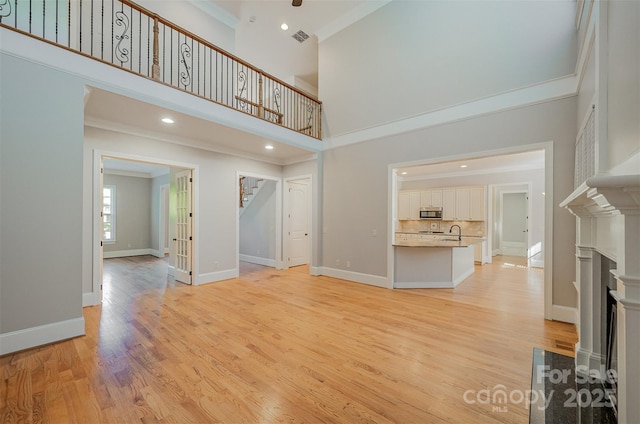 108 Bare Foot Ln, Mooresville, NC 28117 - unfurnished living room with light wood finished floors, ornamental molding, a fireplace, and stairway