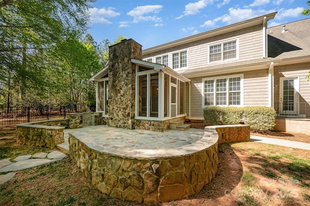 108 Bare Foot Ln, Mooresville, NC 28117 - rear view of house with a chimney, fence, a patio, stone siding, and a sunroom