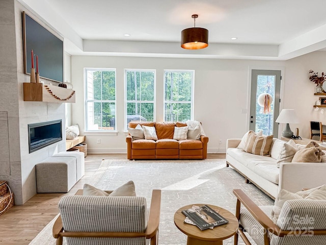 1123 Fern Hill Rd, Mooresville, NC 28117 - living area with light wood-style floors, a tile fireplace, recessed lighting, and a tray ceiling