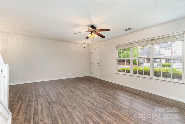 empty room featuring dark wood finished floors, visible vents, ceiling fan, and baseboards