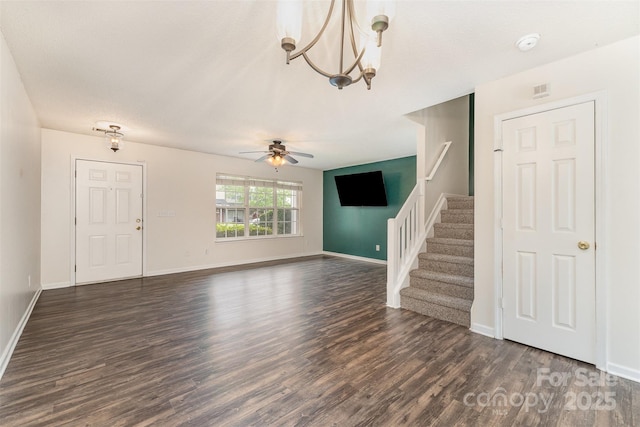 unfurnished living room with dark wood-style floors, ceiling fan with notable chandelier, and stairs