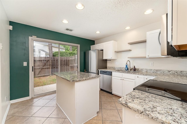 kitchen with stainless steel appliances, open shelves, white cabinets, a sink, and a center island