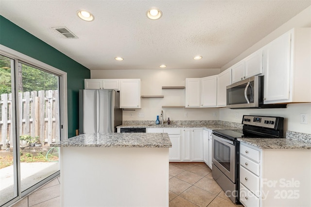 kitchen with open shelves, appliances with stainless steel finishes, white cabinetry, a center island, and light tile patterned flooring