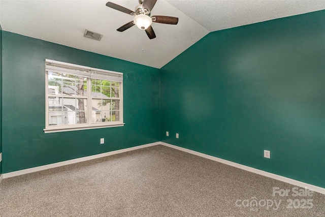 empty room featuring visible vents, ceiling fan, vaulted ceiling, and carpet floors