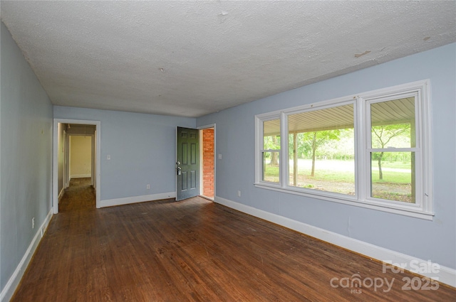spare room with dark wood-style floors, baseboards, and a textured ceiling