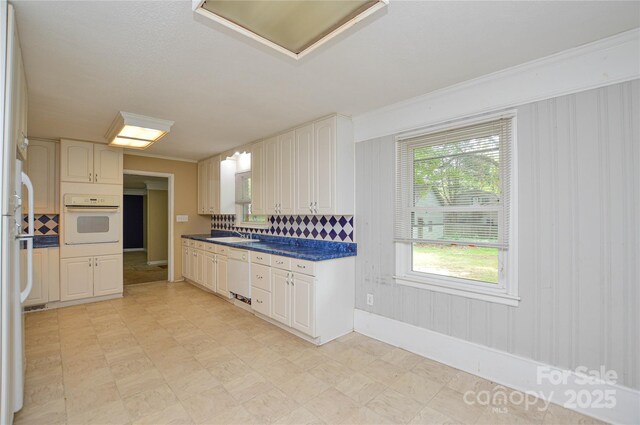 kitchen featuring dark countertops, white appliances, backsplash, and baseboards
