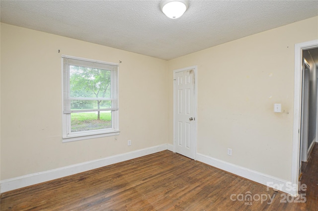 unfurnished room featuring baseboards, a textured ceiling, and dark wood-style flooring