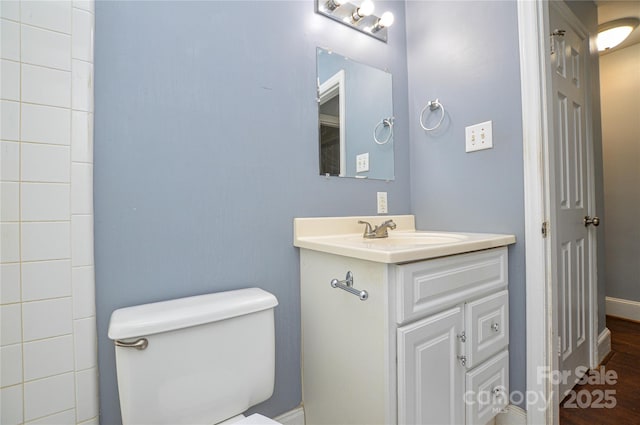 bathroom with wood finished floors, toilet, vanity, and baseboards
