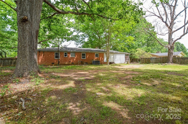 view of yard with a garage, fence, and central AC unit