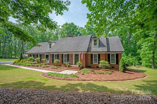 new england style home with a front yard, crawl space, brick siding, a chimney, and roof with shingles