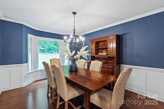 dining area featuring an inviting chandelier, dark wood-type flooring, a wainscoted wall, a decorative wall, and ornamental molding