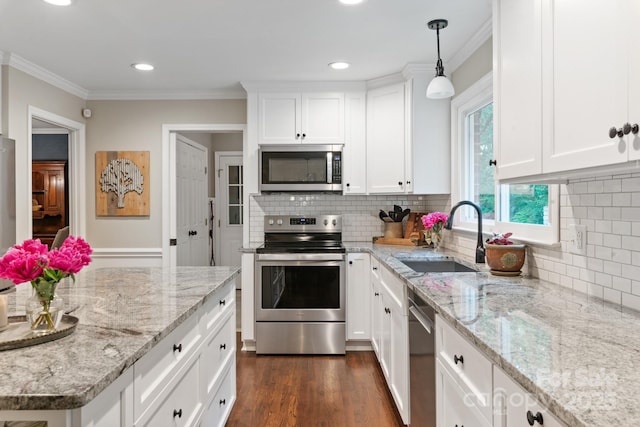 kitchen featuring a sink, stainless steel appliances, crown molding, backsplash, and white cabinets