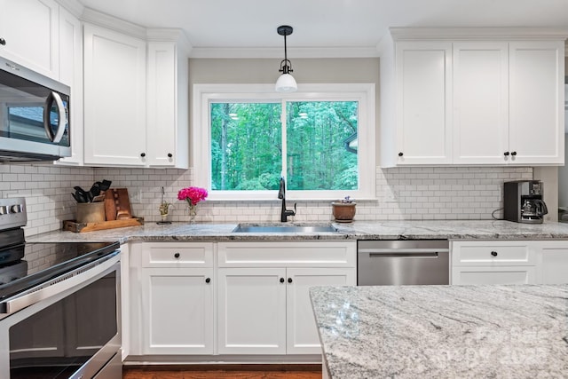 kitchen featuring white cabinetry, appliances with stainless steel finishes, crown molding, and a sink