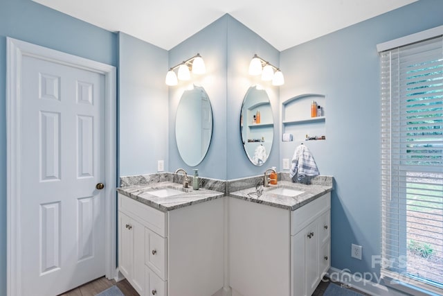 bathroom featuring wood finished floors, double vanity, and a sink