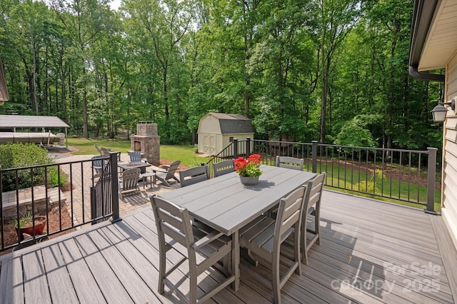 deck with an outdoor structure, a storage shed, outdoor dining area, and a yard