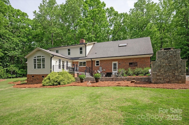 rear view of property with a lawn, crawl space, brick siding, and a chimney