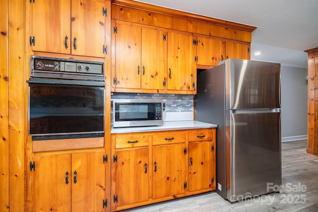 3340 Wrenwood Dr, Newton, NC 28658 - kitchen featuring brown cabinetry, decorative backsplash, stainless steel appliances, light wood finished floors, and baseboards